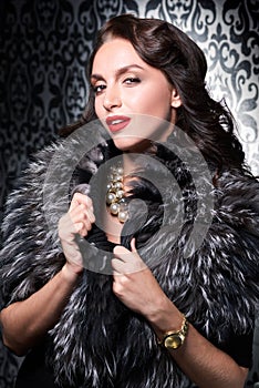 Portrait of brunette retro woman wearing silver fox fur over vintage background