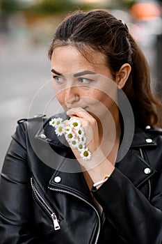 portrait of brunette woman covered face by hand decorated with small daisy flowers