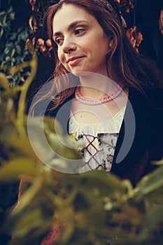 Portrait of brunette woman dressed in historical Baroque clothes with old fashion hairstyle, outdoors