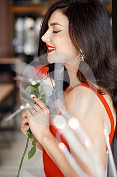 Portrait of brunette woman in elegant red dress standing in restaurant