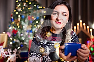 Portrait of brunette woman holding a blue gift box in hands