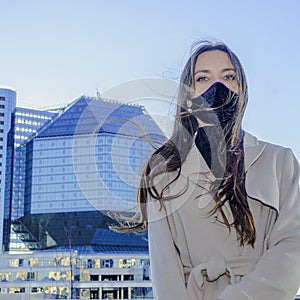Portrait of brunette woman in a protective medical mask on a cityscape background. Virus protection. 2019ncov concept photo