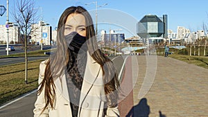 Portrait of brunette woman in a protective medical mask on a cityscape background. Virus protection. 2019ncov concept