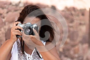 Portrait of a brunette young woman taking a picture with a vintage camera