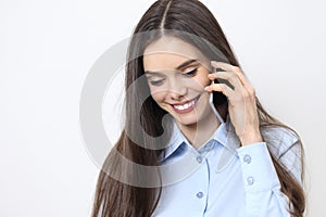 Portrait of brunette young woman talking on the phone looking down smiling isolated on white background