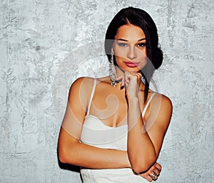 Portrait of brunette young woman in white dress over grey background