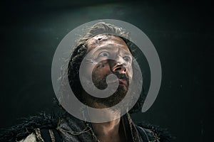 Portrait of a brutal bald-headed viking in a battle mail posing against a black background.