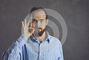 Portrait of brutal bearded hipster man twist mustache stand on grey studio wall