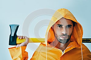 Portrait of brutal handsome man in bright raincoat holding big axe