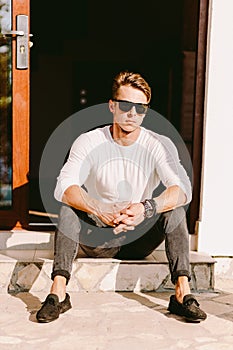 Portrait of a brutal handsome man in sunglasses and watch outdoors