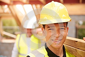 Portrait Of Builder And Apprentice Carrying Wood On Site photo