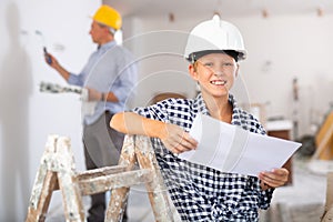 Portrait of builder boy checking blueprints in room being renovated