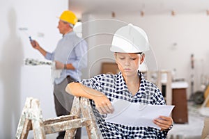 Portrait of builder boy checking blueprints in room being renovated