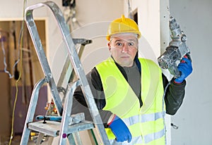 Portrait of builder handyman working with electric drill in repairable room