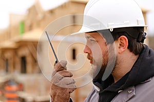 Portrait of builder talking by walkie talkie at construction site.