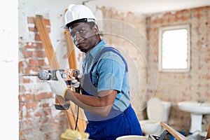 Portrait of builder using electric hammer in apartment