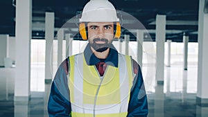 portrait of builder wearing safety clothing and headphones standing in commercial building