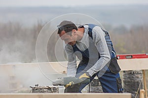 Portrait of builder working with circular saw outdoors, sawdust flying around