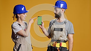 Portrait of building contractors pointing at smartphone