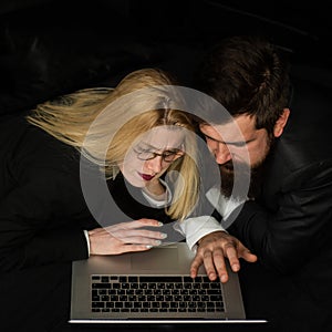 Portrait of a business couple looking at laptop together at dark office.