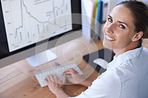 Portrait, business and happy woman at computer with graphs, stock market trading and data analysis. Female worker