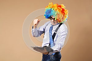 Portrait of business man in clown wig using a tablet to access t