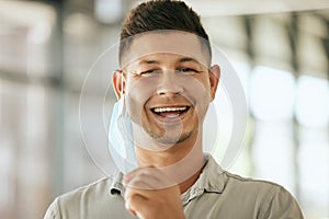 Portrait of business man removing protective face mask off his face to breath freely in the office during COVID-19