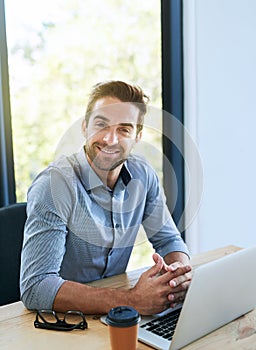 Portrait, business man and smile with laptop in desk at office in startup company as architect. Entrepreneur, table and