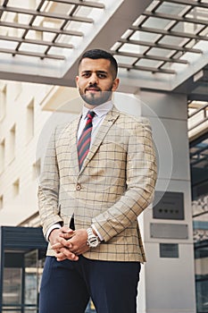 Portrait of a business man in suit outdoors against the backdrop of a glass building downtown.