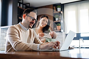 Portrait of business man using laptop working while family in background at home.