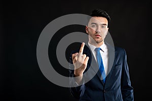 Portrait of business man wearing blue business suit and tie showing obscene gesture