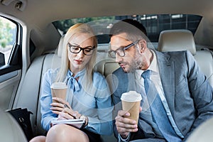 portrait of business people with coffee to go working on project on back seats photo