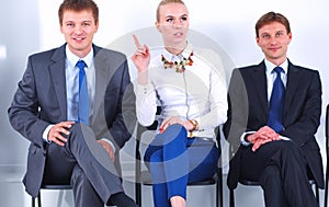 Portrait of business people sitting on chairs by office door