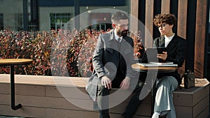 Portrait of business people talking analyzing documents sitting outside in open air cafe