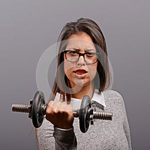 Portrait of business woman lifting weights against gray background