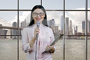 Portrait of business woman with a microphone and clipboard.