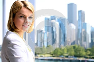 Portrait of business woman standing near window. Downtown area background