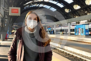 Portrait of business woman waiting train wearing medical protective mask at train station in winter