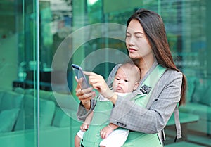 Portrait of business woman working by smartphone with carrying her infant