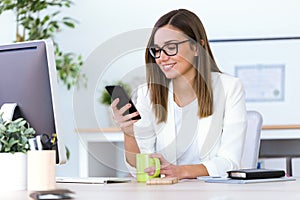 Business young woman using her mobile phone in the office.