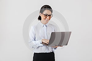 Portrait of businesslike woman wearing eyeglasses holding silver laptop in the office, isolated over white background