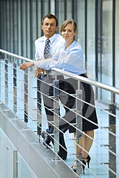 Portrait of businessman and businesswoman standing by railing