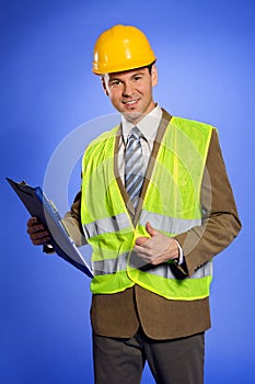 Portrait of businessman in coveralls holding clipboard and showing thumbs up sign
