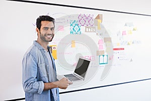 Portrait of businessman with laptop against whiteboard