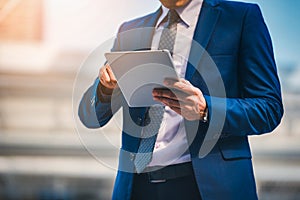 Portrait of businessman looking digital tablet on blurred background. Business success concept