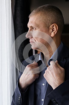 Portrait of a businessman looking out the window, holding on to his collar