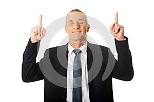 Portrait of businessman pointing upwards