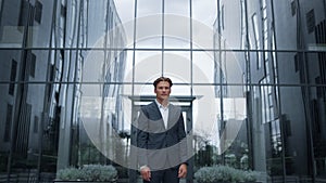 Portrait businessman posing at modern glass office building alone.