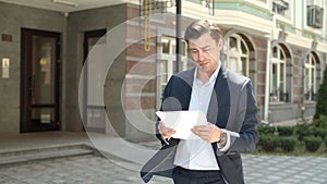 Portrait businessman reading documents outdoor. Man studding papers at street