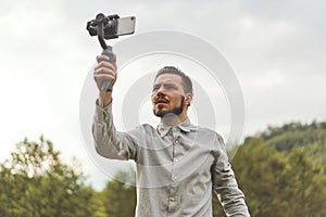 Portrait of businessman recording video presentation at smartphone with steadycam